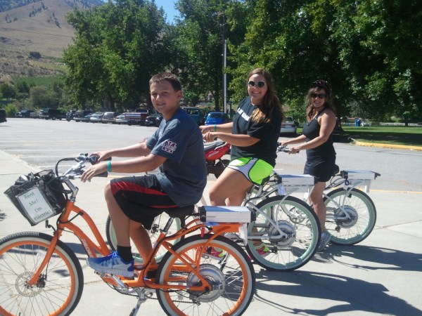 a little girl riding on the back of a bicycle