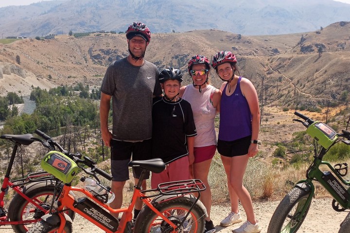 a group of people standing around a motorcycle in front of a mountain